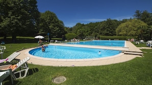 A rectangular swimming pool with a tiled deck surrounding it, set in a grassy area with trees in the background. - Rododendro Rosso in Ispra (Ispra)