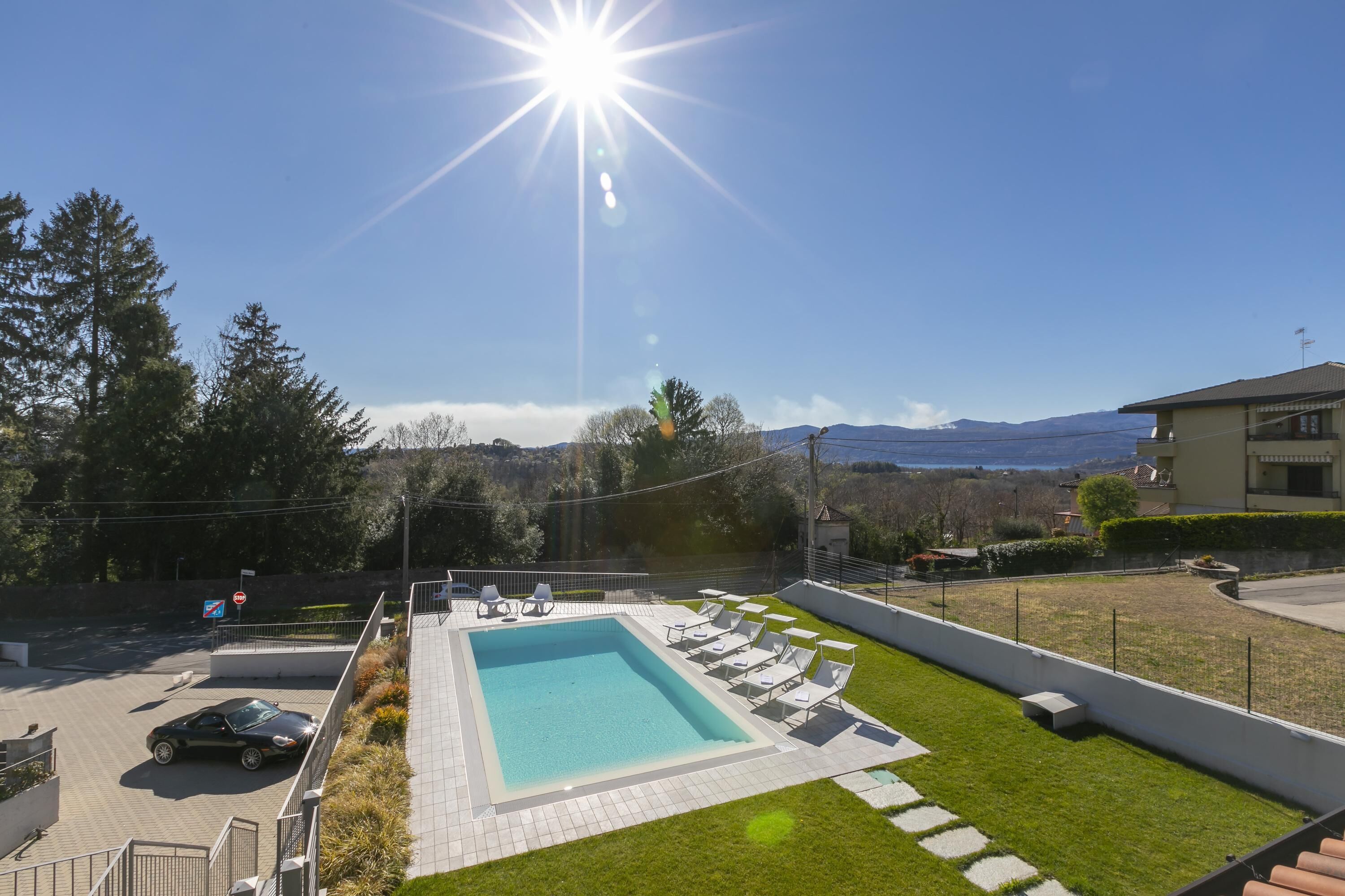 Une piscine entourée de chaises longues, avec une pelouse bien entretenue et une vue sur les montagnes lointaines.