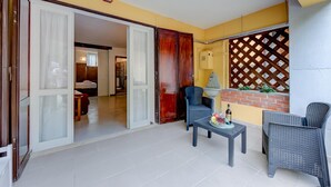 A balcony with wicker furniture, a table with fruit, and a sliding door leading to a room. - Vicolo 42 At 200m From Lake (Salò)