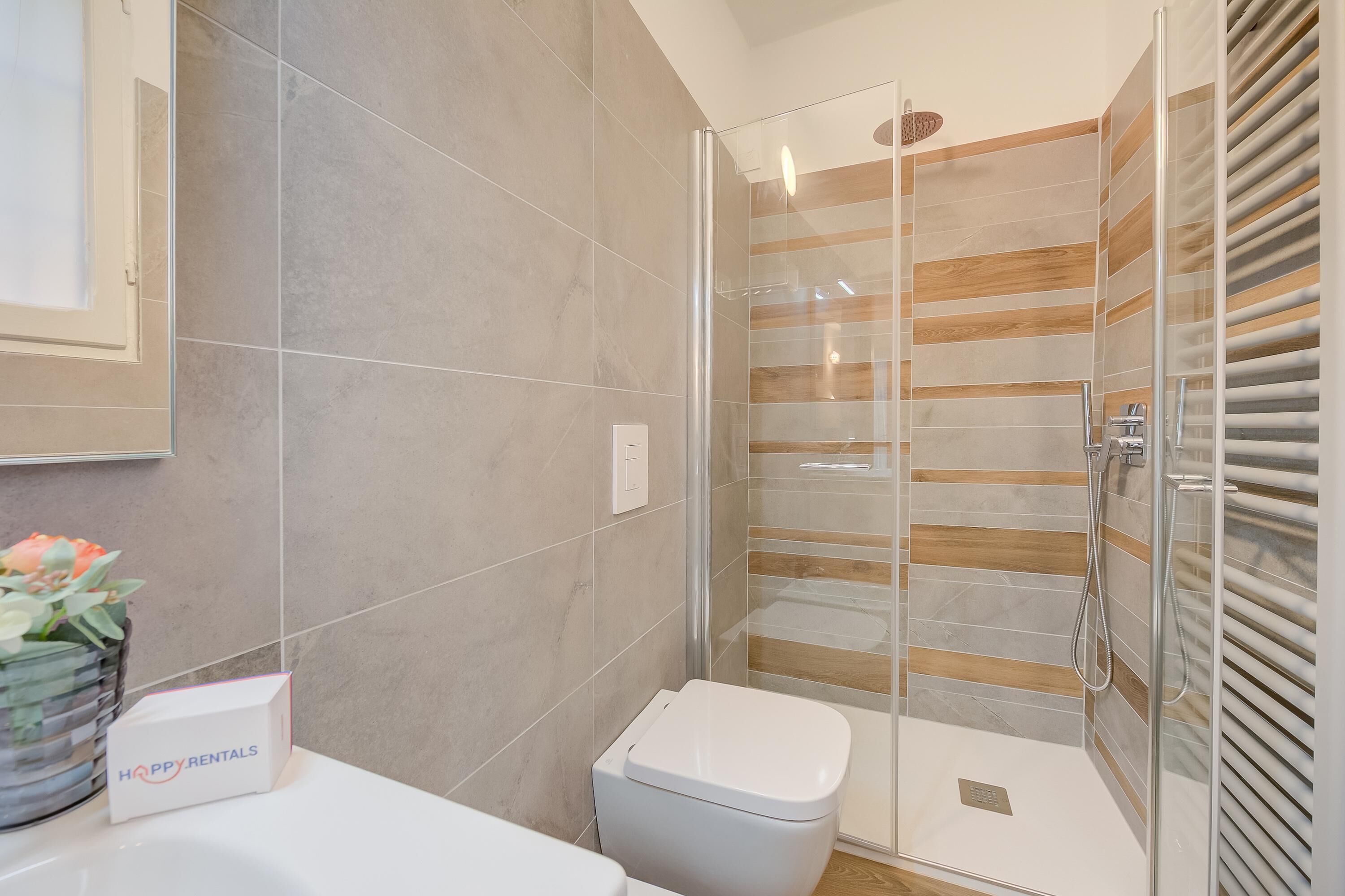 A modern bathroom with a glass shower enclosure, a toilet, and a sink.