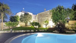 A swimming pool with a stone building in the background. - Villa Pruno in Scicli (Scicli)