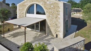 A stone building with a large arched window and a covered patio area. - Villa Pruno in Scicli (Scicli)