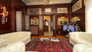 Ein luxuriöses Wohnzimmer mit einem roten Teppich mit Muster, weißen Ledersofas und einem Fernseher.