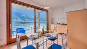 A balcony with a table set for dining, overlooking a mountainous landscape. - Va Pensiero sul Lago Stunning View (Tronzano Lago Maggiore)