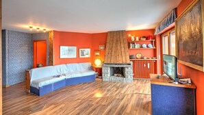 A living room with a sofa, fireplace, and a television on a stand. - Terrazza Dei Principi Few Steps From Ski (Sestriere)