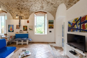 Una sala de estar con techo de piedra, televisor, sofá y obras de arte en las paredes.