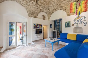 Relax in this stylish living room with a sofa, table, and TV, plus doors leading to other rooms and a window with an outside view.