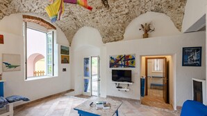 Ένα ευρύχωρο σαλόνι με ψηλό ταβάνι, μια τηλεόραση τοποθετημένη στον τοίχο και ένα τζάκι.