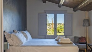 Ein Schlafzimmer mit Bett, einem Sessel, einer Lampe und Blick ins Freie.