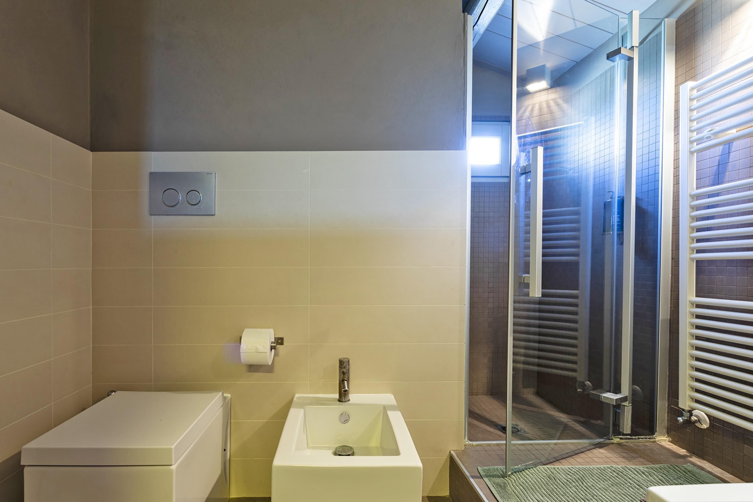 Un baño moderno con inodoro, lavamanos y cabina de ducha de vidrio.