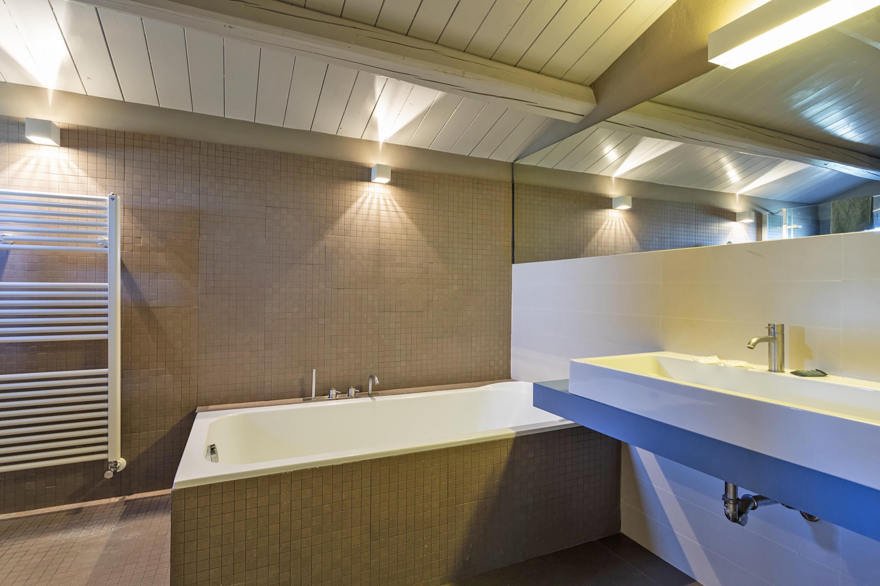 A modern bathroom with a bathtub, a sink, and a towel rack.