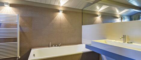 A modern bathroom with a bathtub, a sink, and a towel rack.