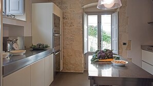 Eine moderne Küche mit Steinwand, Edelstahlgeräten und Blick ins Grüne.