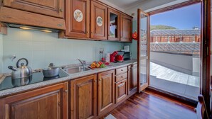 A kitchen with wooden cabinets, a stove, and a sink. - Sestriere Terrace Apt Few Steps From Ski (Sestriere)