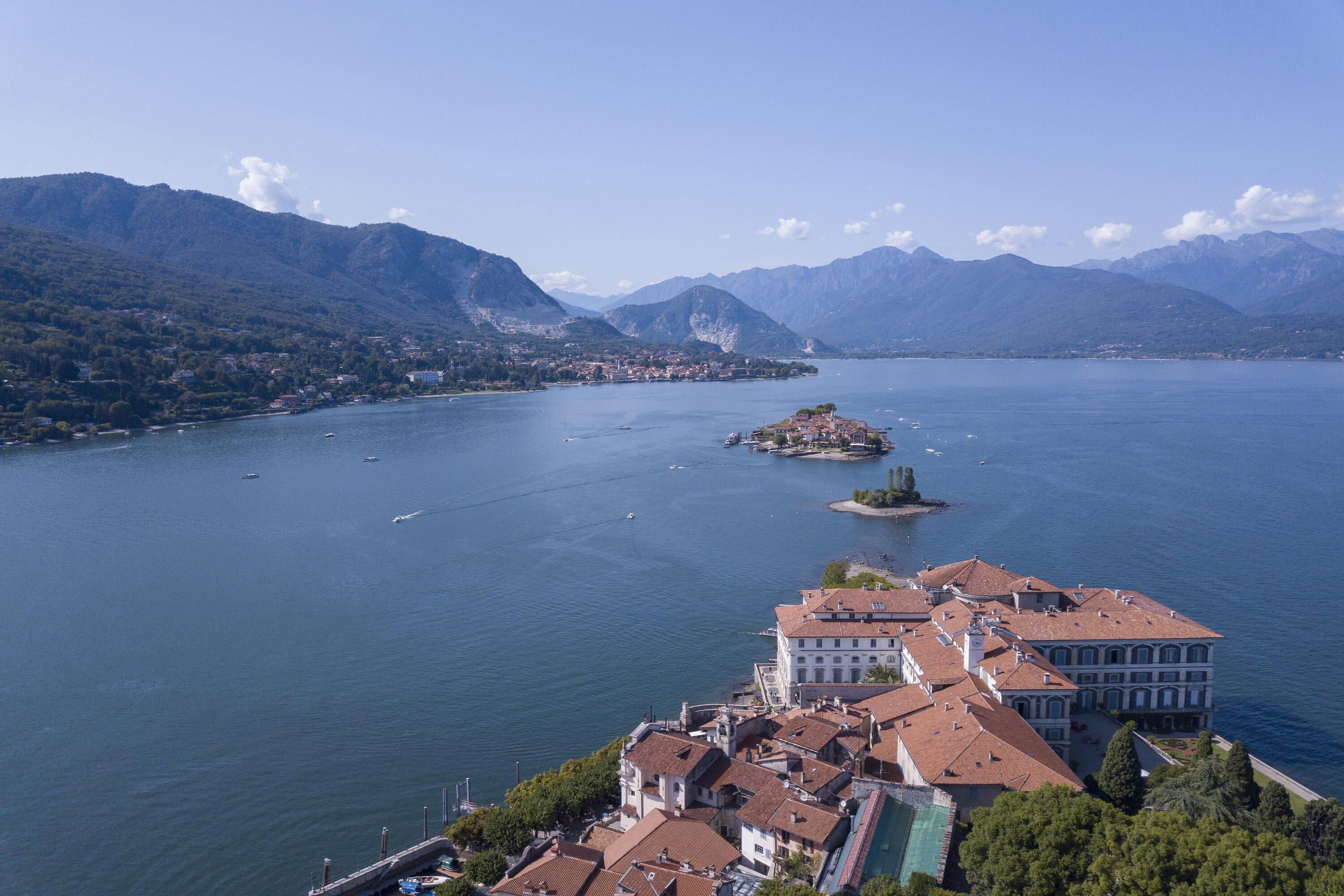 A lakeside town with historic buildings, a small island, and mountains in the background.