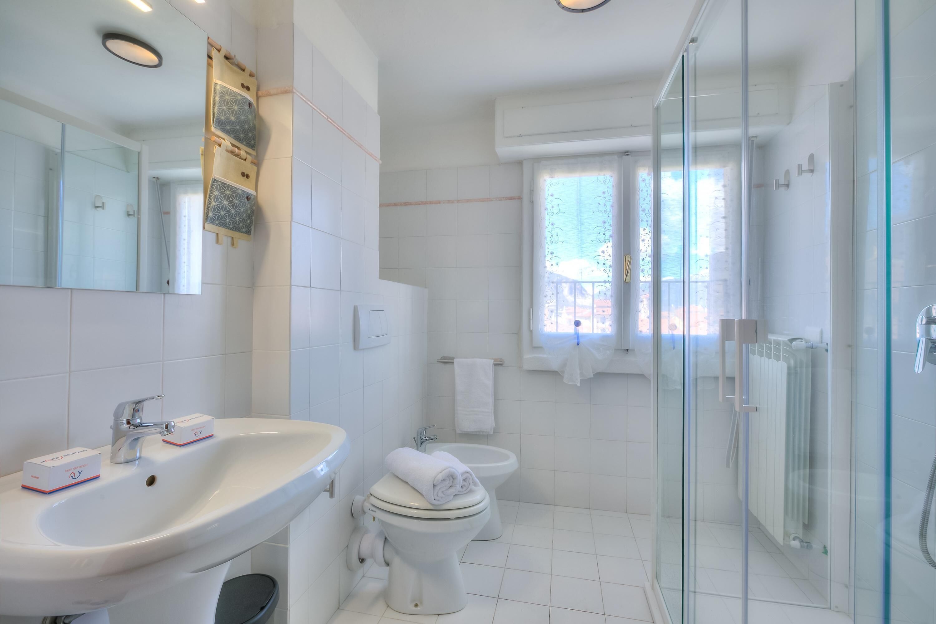 Une salle de bain moderne avec une douche à parois de verre, un lavabo blanc et des toilettes.