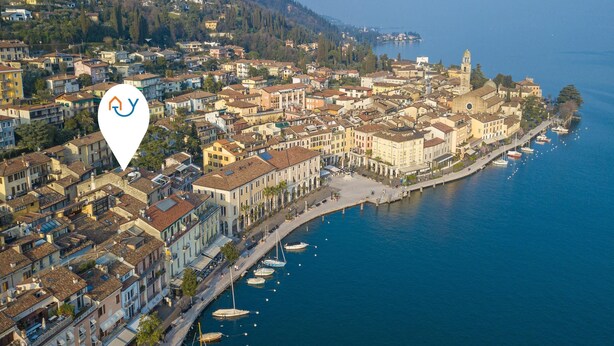 An aerial view of a coastal town with historic buildings, a marina, and a prominent church tower. - Residenza Faust-historical Center Sal (Salò)
