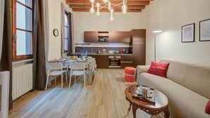 A modern kitchen with a microwave, oven, and dining area with chairs and a table. - Residenza Faust-historical Center Sal (Salò)