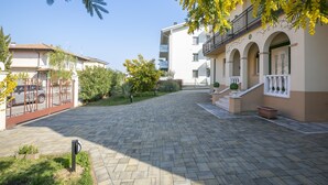 Un patio con un sendero adoquinado, una entrada con reja y un edificio con balcones y ventanas arqueadas.