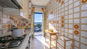 A kitchen with a stove, pots, and a view of the outdoors. - Rossella Lake View in Salo (Salò)