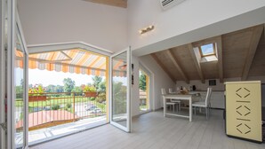Une pièce spacieuse avec un balcon, un coin repas et une cuisine.