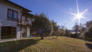 Une maison à deux étages avec un balcon, une cour verdoyante et un ciel dégagé.