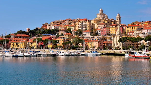 A coastal town with colorful buildings, a prominent church, and a marina with boats. - Sunrise Apartment Seaview (Imperia)