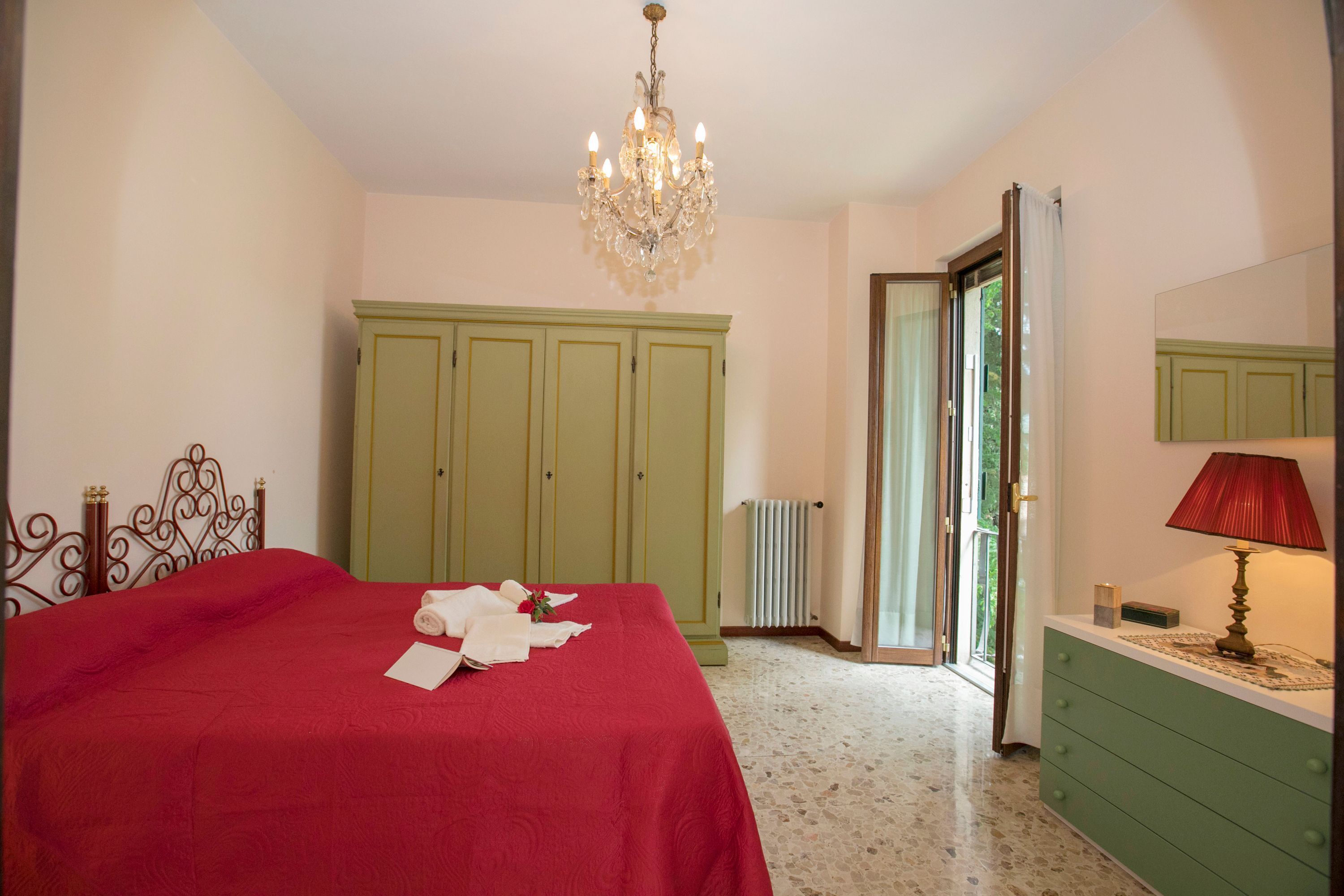 Una camera da letto con un letto, un lampadario, un armadio verde e un termosifone.
