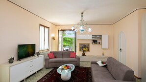 Een woonkamer met een bank, televisie, salontafel en een kroonluchter.