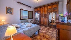 Una camera da letto con un letto, un comodino, una cassettiera, uno specchio e una finestra con vista.