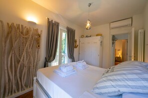 A hotel room with a bed, neatly folded towels, a wooden wall decoration, a wardrobe, and an air conditioning unit.