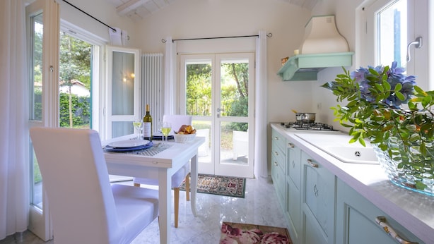 A kitchen with a dining table, chairs, a stove, and a window with curtains. - Villa Victor 100m From sea (Massa)