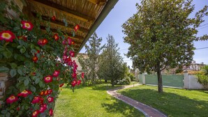 A garden with a brick wall, a wooden pergola, and a pathway leading to a green gate. - Villa Clara few km From the sea (Pietrasanta)