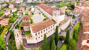 Vue aérienne d’un bâtiment historique doté d’une cour intérieure, entouré d’arbres et de voitures garées.