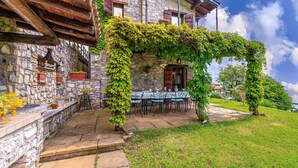 A stone building with a covered patio, a table with chairs, and a view of the sky. - Villa Formaga in Hilly Area Relax and vie (Gargnano)
