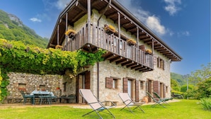 A stone building with wooden balconies, outdoor seating, and a garden. - Villa Formaga in Hilly Area Relax and vie (Gargnano)