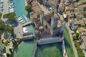 An aerial view of a historic fortified castle with a moat, surrounded by residential buildings and a marina with boats. - Vistalago Green Residence 100m From Lake (Desenzano del Garda)