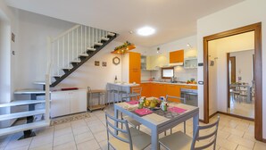 A modern kitchen with a dining area, a staircase, and a view into another room. - Vistalago Green Residence 100m From Lake (Desenzano del Garda)