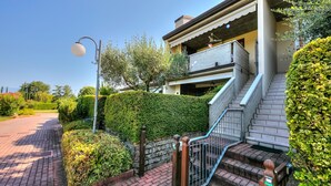 A residential building with a staircase leading to a balcony, surrounded by well-maintained hedges and a clear sky. - Vistalago Green Residence 100m From Lake (Desenzano del Garda)