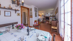 A dining area with a table set for four, a chandelier, and a view into the living room. - Villino di Corsanico With View (Massarosa)