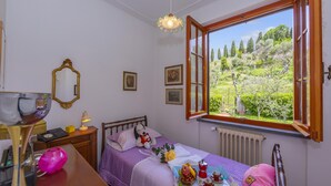 A bedroom with a bed, a window with an open shutter, a dresser, a mirror, and a radiator. - Villino di Corsanico With View (Massarosa)