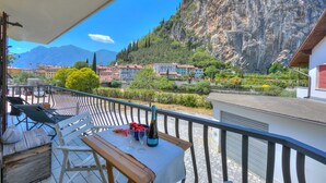 A balcony with a table set for two, overlooking a mountainous landscape with buildings and greenery. - The Rock View in Arco (Arco)