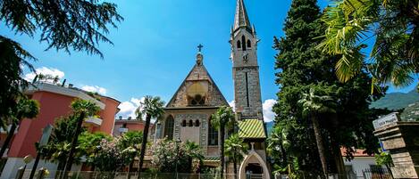 Una iglesia con un campanario alto y un edificio más pequeño con una cruz en la parte superior.