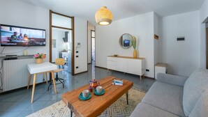 A modern living room with a television, wooden coffee table, grey sofa, and a white cabinet. - The Rock View in Arco (Arco)