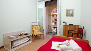 A bedroom with a red bed, a wooden chair, a small table, and a wardrobe. - Villa Mimosa - Appartamento 1 (Desenzano del Garda)