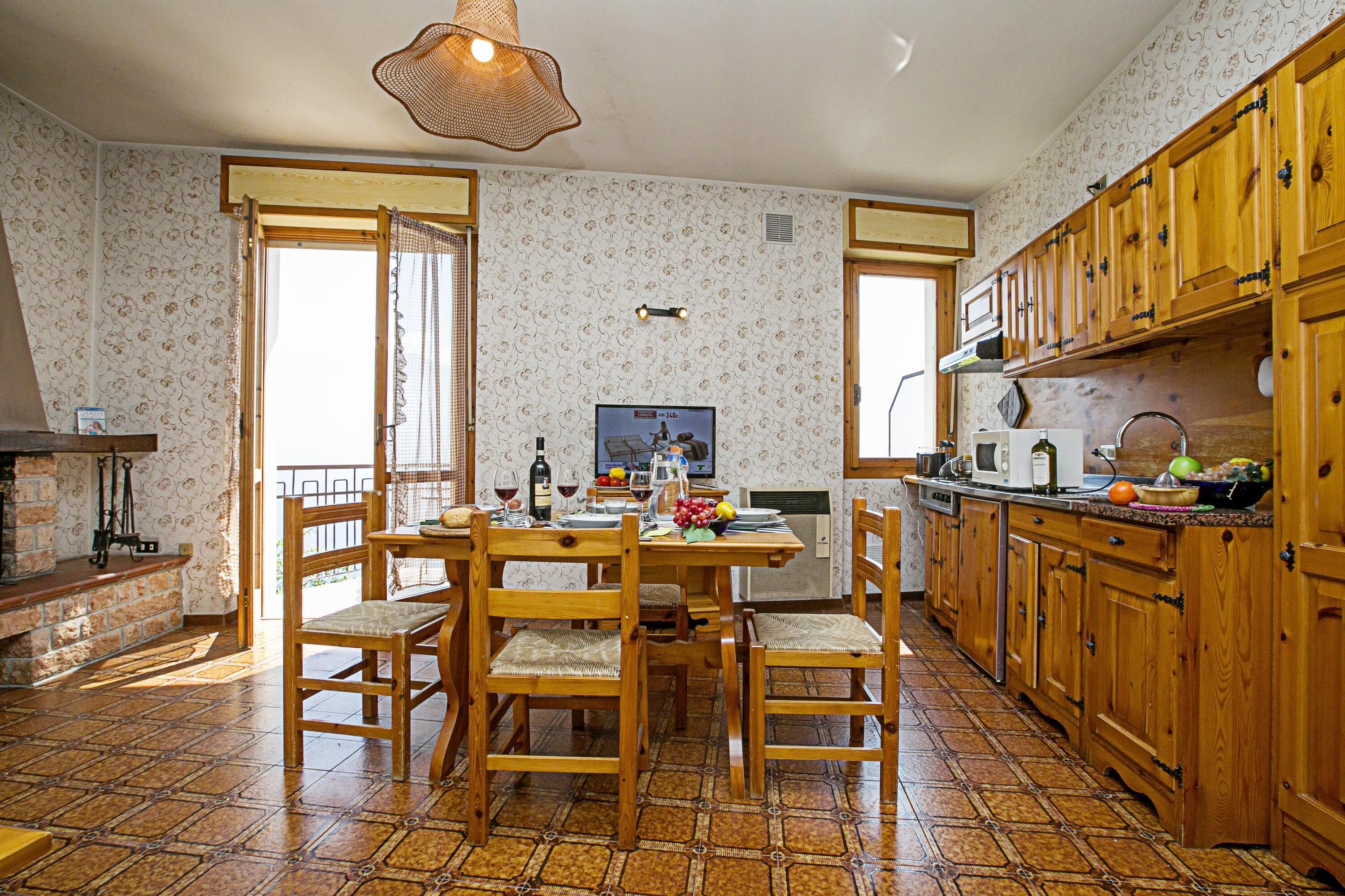 Una cocina con armarios de madera, suelo de baldosas y una mesa de comedor lista para cuatro personas.