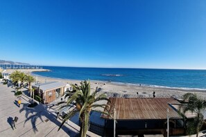A beachside promenade with a view of the sea, palm trees, and a building with a sign reading "Hotel". - Tre Balconi Sul Mare Beach (Borghetto Santo Spirito)