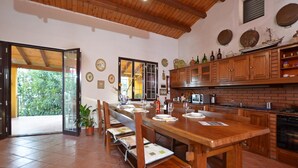 A spacious kitchen with a wooden table and benches, a brick wall, and a large window. - Villa Torres in Scicli (Scicli)