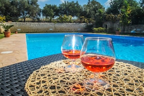 A poolside setting with two glasses of red wine on a woven mat. - Villa Torres in Scicli (Scicli)