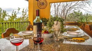 A table set for dining with a bottle of red wine, glasses, plates, and a bowl of fruit. - Villa Torres in Scicli (Scicli)